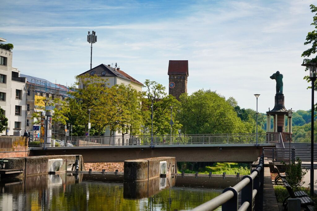 Picturesque view of a bridge and clock tower in Pforzheim, Germany, surrounded by lush greenery.